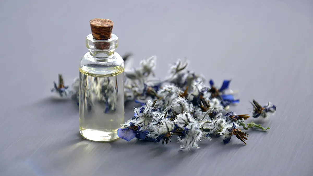 Essential oil bottle with dried herbal flowers for natural massage therapy.